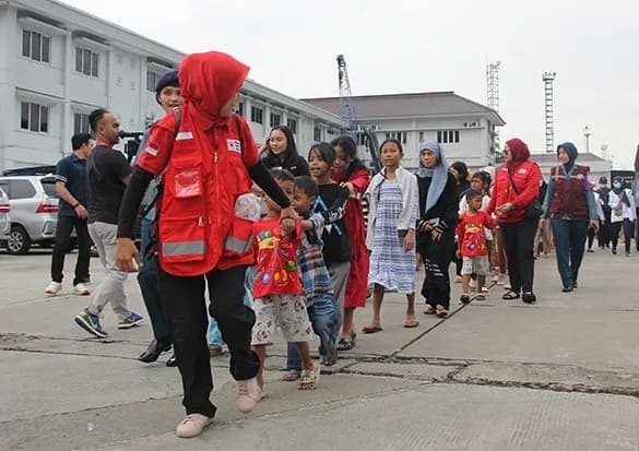 Potret relawan dan staf PMI DKI Jakarta dengan latar Monas dan cakrawala kota Jakarta saat senja.