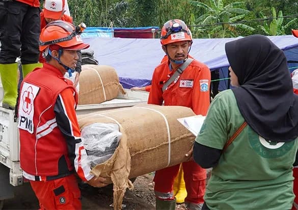 Relawan PMI mengevakuasi warga menggunakan perahu karet di jalan yang terendam banjir.